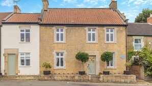 A two-story stone house with a red-tiled roof, white-framed windows, and a green door. There are potted plants on the front steps. - 5 bedroom accommodation in Chesterfield (Chesterfield)