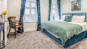 A bedroom with a large bed, a chair, a small table with a vase of flowers, and a painting on the wall. - 5 bedroom accommodation in Chesterfield (Chesterfield)