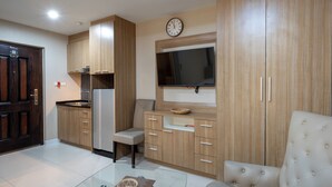 A modern kitchen with wooden cabinets, a built-in stove, and a flat-screen TV mounted above the cabinets. - New Nordic Trend 2 by Apartwell (Pattaya)
