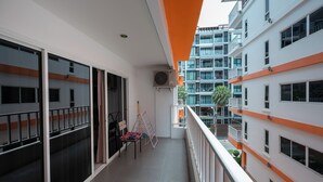 A balcony with a view of adjacent buildings, a ceiling fan, and a chair. - New Nordic Trend 2 by Apartwell (Pattaya)