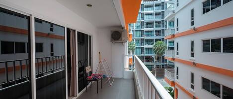 Un balcon donnant sur les bâtiments voisins, un ventilateur de plafond et une chaise.