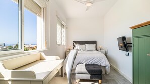 Une chambre à coucher moderne avec un lit, un banc et un téléviseur fixé au mur.
