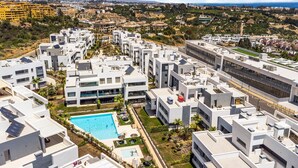 A modern residential complex with a central swimming pool, surrounded by white buildings with flat roofs and solar panels. - Cozy apartment in Estepona (Estepona)