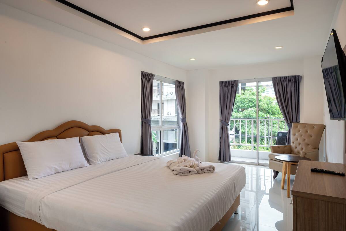 A hotel room with a large bed, a chair, a small table, and a TV.