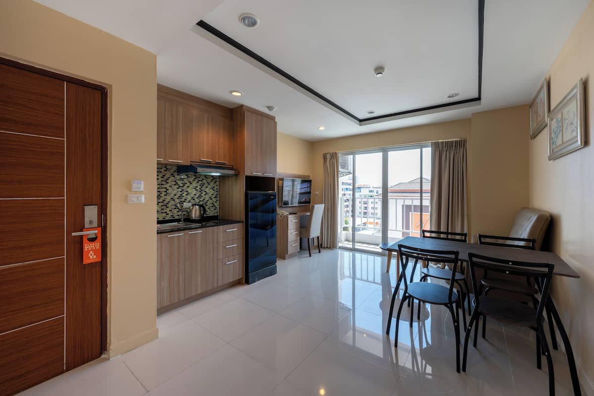 A modern kitchen with wooden cabinets, a built-in oven, and a dining area with a table and chairs.