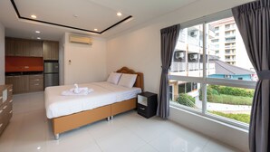A modern hotel room with a bed, bedside table, and a view of the outside. - New Nordic Trend 5 by Apartwell (Pattaya)