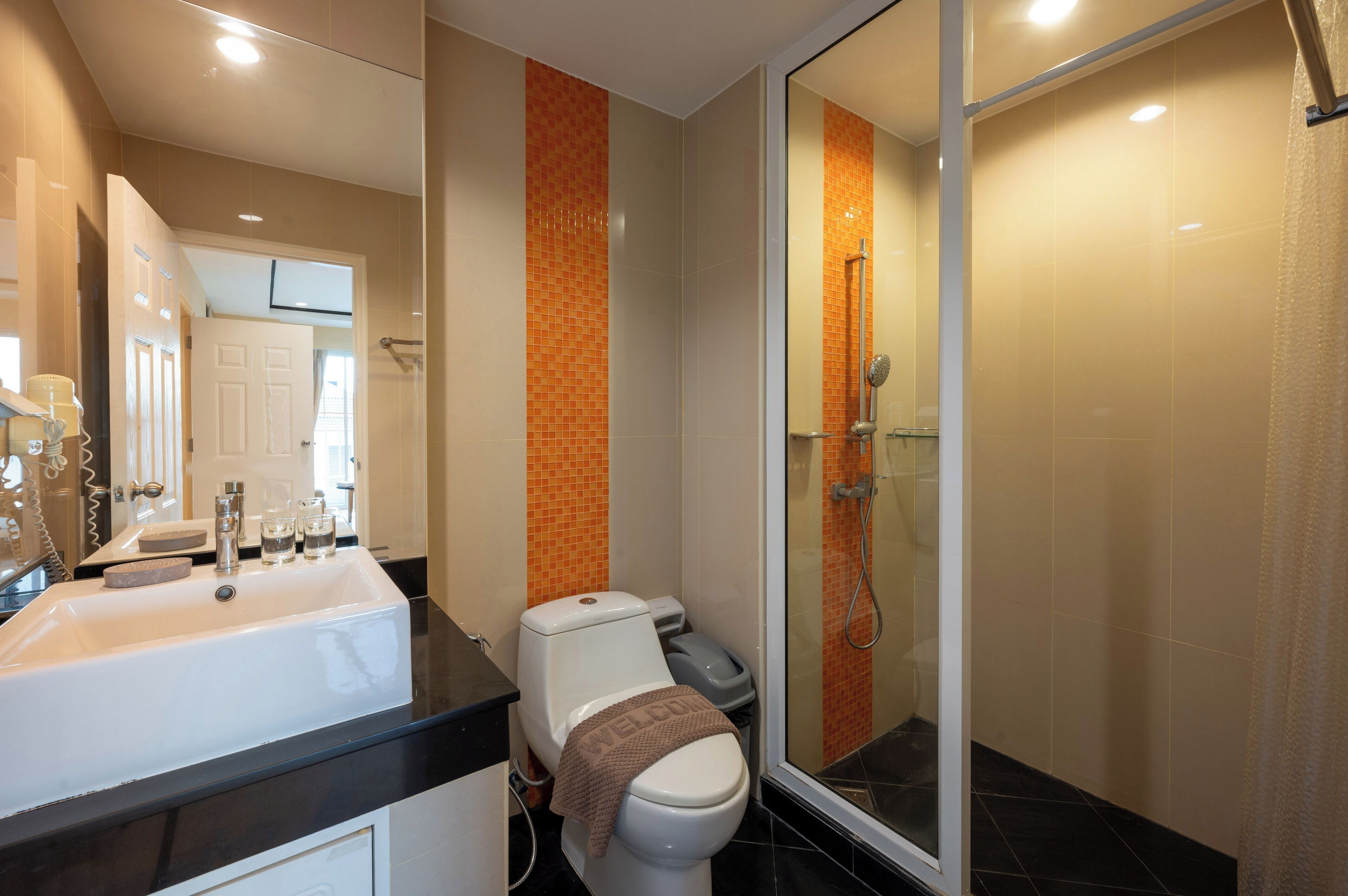 Un baño moderno con un lavamanos grande, inodoro y ducha con mampara de vidrio.
