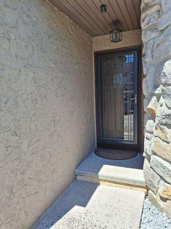 A stone exterior wall with a door and a small porch area. - nestled against the dunes, south end beach block on cul-de-sac (Brigantine)