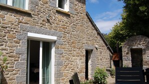 A stone building with a large sliding glass door, a small window, and a chimney. - Charme Breton à 20 min de Saint-malo - 2 Chambres à 500 m du Golf du Tronchet (Le Tronchet)