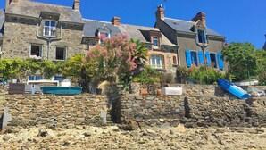 A stone building with multiple windows and a balcony, surrounded by greenery and a stone wall. - Charme Breton à 20 min de Saint-malo - 2 Chambres à 500 m du Golf du Tronchet (Le Tronchet)