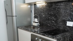 A compact kitchen with a stainless steel refrigerator, a built-in oven, and a granite countertop. - Palermo Cultura Arte y Entretenimiento (Buenos Aires)