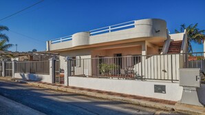 Une maison moderne à deux étages, dotée d’un balcon, d’une entrée sécurisée et d’un petit patio.