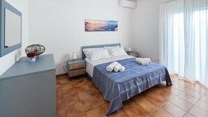 Une chambre d’hôtel avec un lit, une table de chevet, un climatiseur fixé au mur et une fenêtre avec des rideaux.