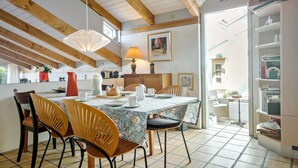 A dining area with a table set for four, wooden chairs, a hanging light fixture, and a view of the adjacent room. - 3 bedroom beautiful home in Kalundborg (Kalundborg)