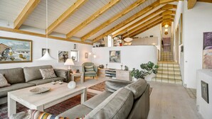 A spacious living room with high ceilings and exposed wooden beams, a cozy sofa set, a coffee table, and a staircase leading to an upper level. - 3 bedroom beautiful home in Kalundborg (Kalundborg)