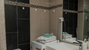 A modern bathroom with a large mirror, a sink, and a towel rack.
