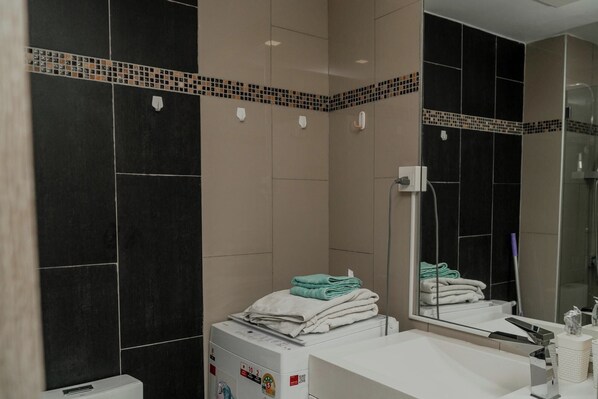 A modern bathroom with a large mirror, a sink, and a towel rack.