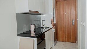 A compact kitchen with a black countertop, stainless steel sink, and a wooden door.