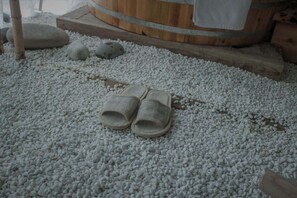 A pair of slippers on a textured white surface, a wooden barrel, and a stone slab. - Hide and see  (Chongqing)