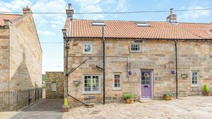 A stone building with a tiled roof, a purple door, and a sign indicating it is a pub.