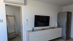 Una cocina moderna con refrigerador empotrado, televisor de pantalla plana en la pared y encimera de madera.