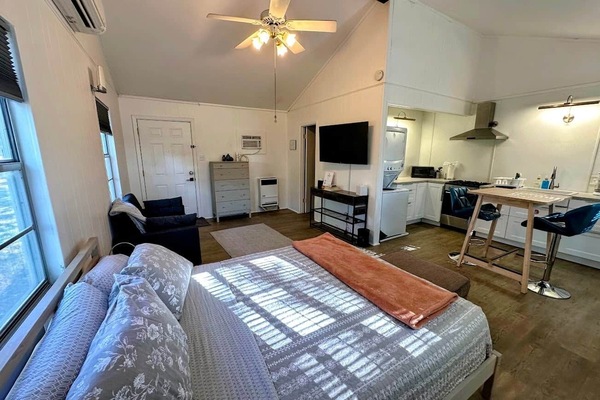 Sleeping, living, and kitchen areas. Bright and clean with a high ceiling.