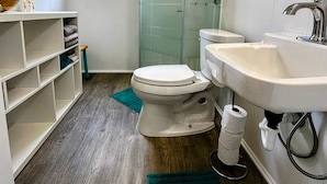Ein kleines Badezimmer mit Toilette, Waschbecken und einer Duschkabine aus Glas.