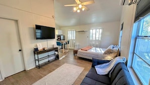 Ein modernes Schlafzimmer mit Bett, Sofa, Fernseher und Schreibtisch.