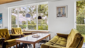 Een kamer met een groot raam, een tafel, twee stoelen en een bank.