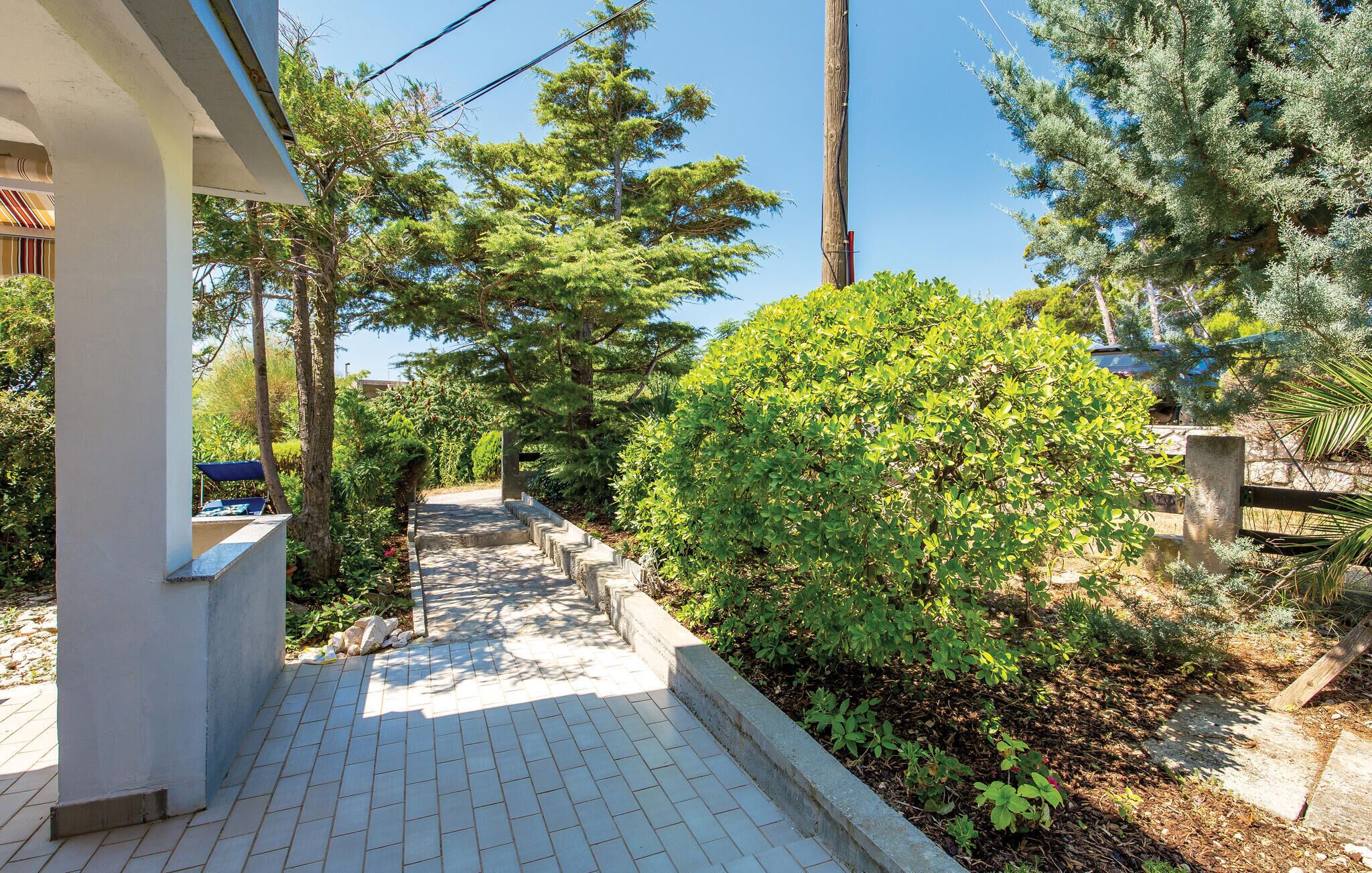 A paved pathway leading to a building with a covered seating area.