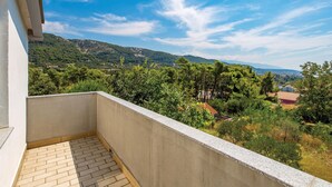 Een balkon met uitzicht op een bergachtig landschap en een dorp daaronder.