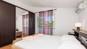 Een moderne slaapkamer met een groot bed, een nachtkastje met een lamp en een kledingkast.