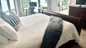 Een slaapkamer met een groot bed, een bureau en een televisie. Het heeft uitzicht op de omgeving.