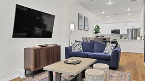 Una sala de estar moderna con un sofá azul, una mesa de centro y un televisor montado en la pared.