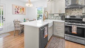 Une cuisine moderne avec des meubles blancs, un grand îlot central, des appareils en acier inoxydable et un crédence décorative.