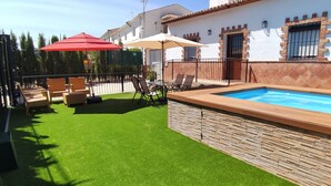 A backyard with a swimming pool, artificial grass, and outdoor furniture.