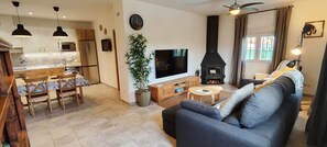 Ein modernes Wohnzimmer mit Sofa, Fernseher, Kamin, Essbereich und Küche.