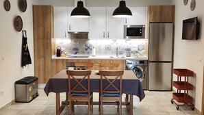 A kitchen with wooden cabinets, a stainless steel refrigerator, a microwave, and a washing machine.