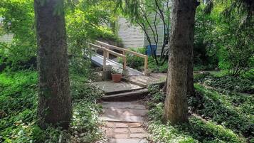 A stone pathway leading to a wooden staircase surrounded by lush greenery.