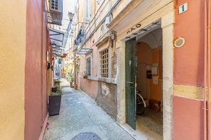 Un callejón estrecho con edificios a ambos lados, una bicicleta estacionada frente a un comercio y una tapa de alcantarilla en el suelo.