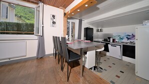 Een moderne keuken met een eethoek, een houten plafond en uitzicht op een glooiend groene heuvel.