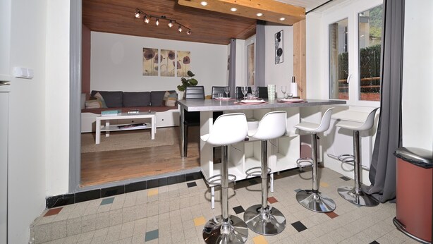 Een moderne keuken met een eethoek, barstoelen en een bank.