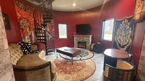 A living room with a fireplace, a spiral staircase, and a large tapestry. -  Hogwarts Themed Castle!  10 Acres - An Amazing Experience! (Westfield)