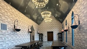 A spacious hall with long tables and benches, brick walls, and multiple hanging chandeliers. -  Hogwarts Themed Castle!  10 Acres - An Amazing Experience! (Westfield)