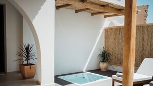 En modern uteplats med en bubbelpool, solstolar och krukväxter.