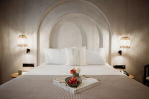 A neatly made bed with white linens, a tray with fruit and flowers, and two wall-mounted lamps. - Kalani Residence (Nestos)