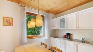 Eine Küche mit weißen Schränken, einem Holztisch und einem Fenster mit Vorhängen.