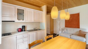 Eine moderne Küche mit weißen Schränken, einer Kaffeemaschine und einem Essbereich mit einem Holztisch und Stühlen.