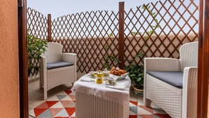 Un balcon agrémenté de meubles en osier, une table avec un service à thé et une clôture en treillis.