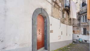 En smal brostensgade med en røddør og hvide vægge, der antyder et historisk eller traditionelt miljø.